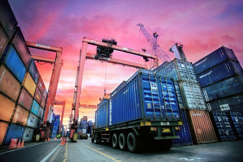Side view of a lorry driving on a road with the sunset reflected on the side